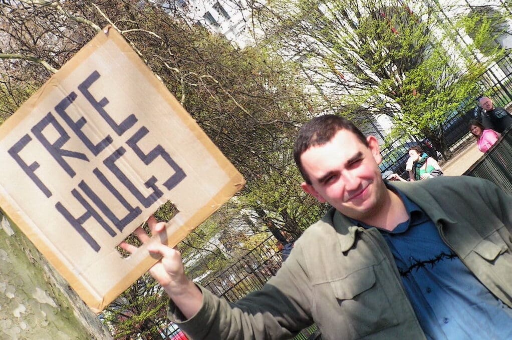 photo of man holding sign that says "FREE HUGS"