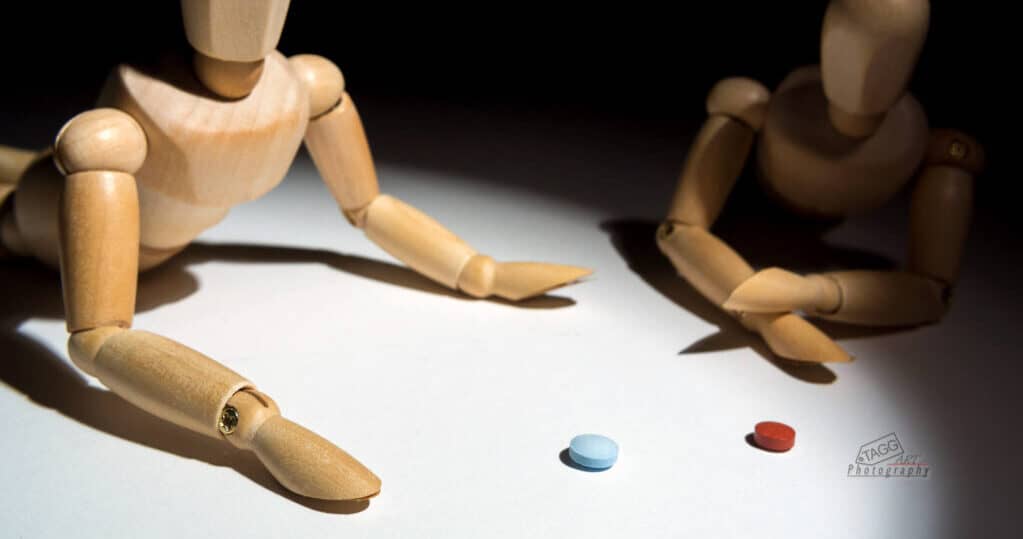 two artist mannequins looking at red and blue pills