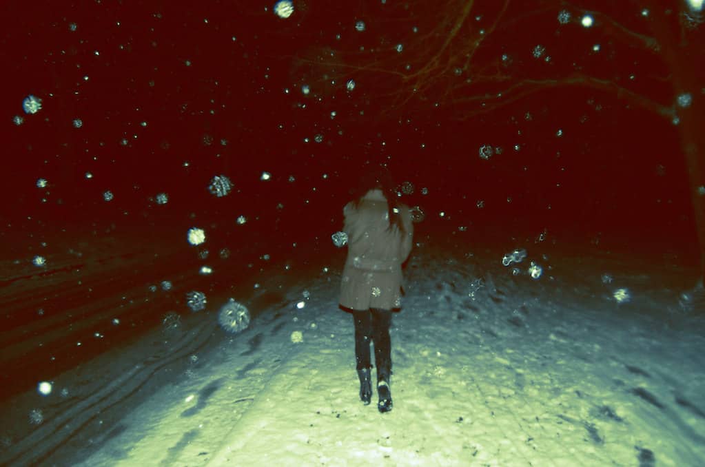 photo of woman walking in snow at nigh