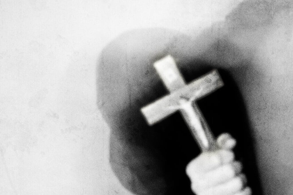 photo of mysterious figure holding up a cross