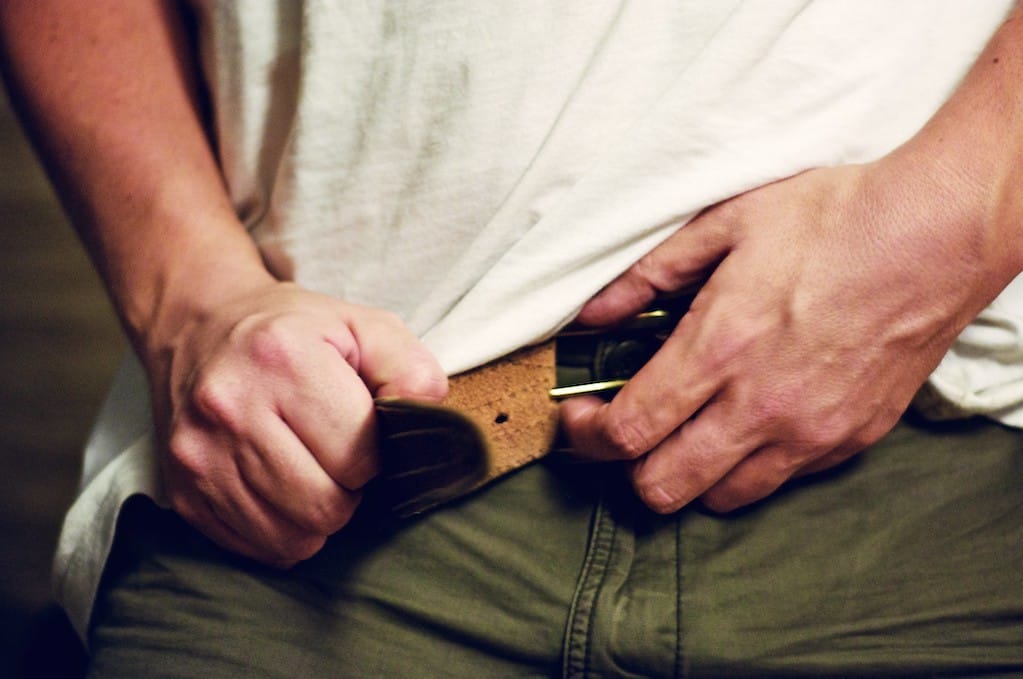 photo of hands fastening belt buckle