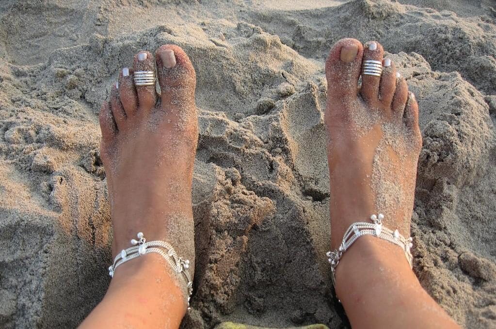 photo of sandy feet with rings on toes