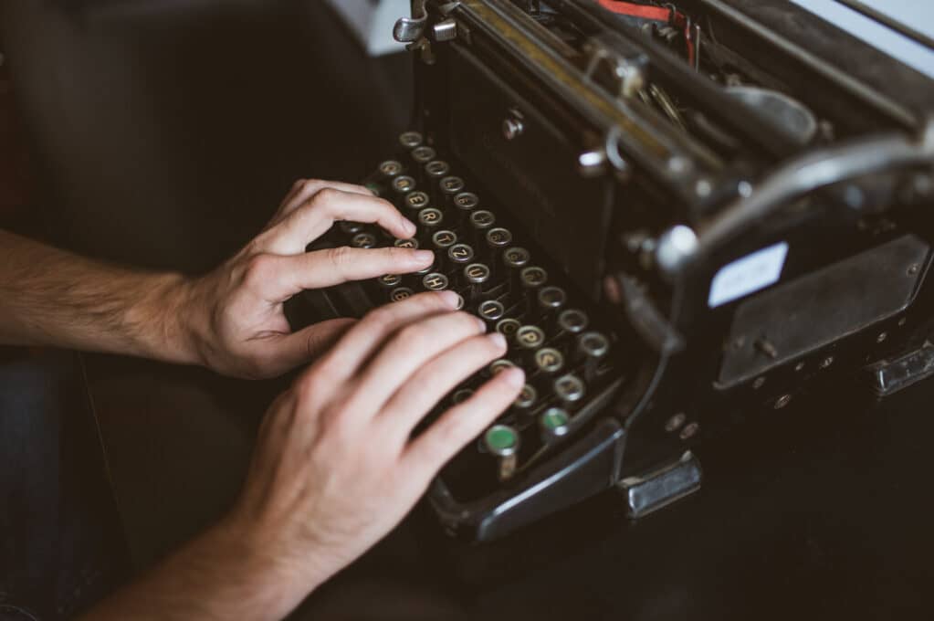 photo of hands typing on old typewriter