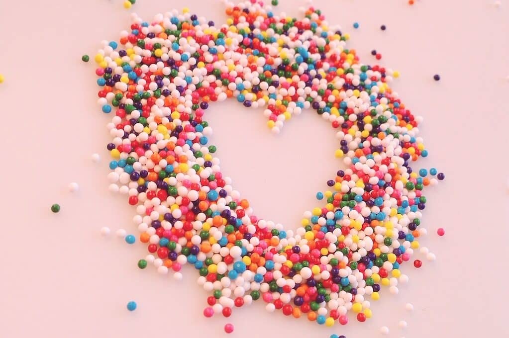 photo of rainbow sprinkles formed into a heart shape
