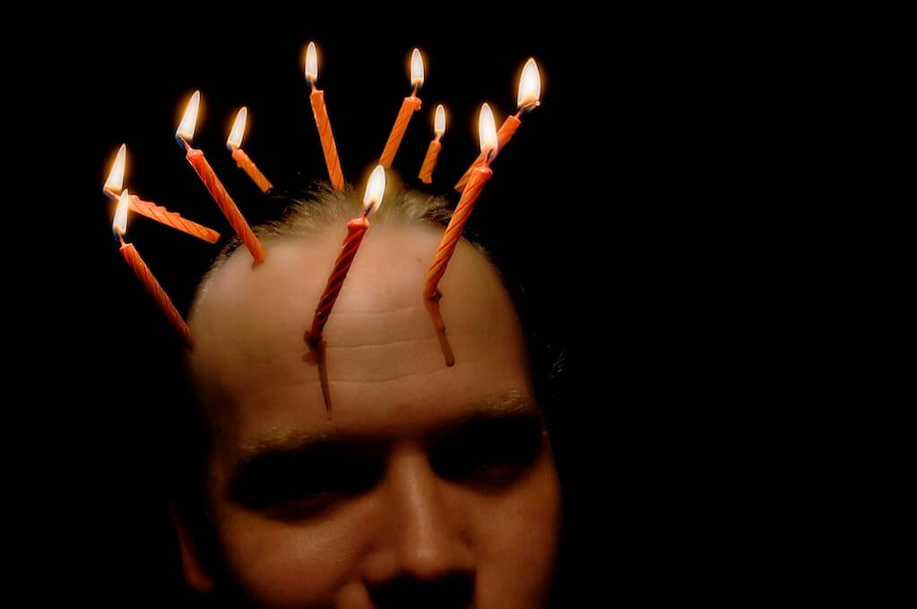 photo of man with lit candles attached to his head