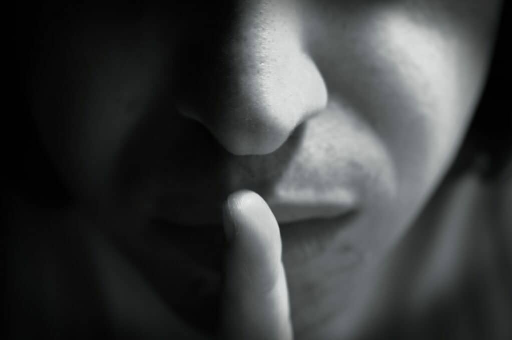 photo of person holding finger up to lips to signal quiet