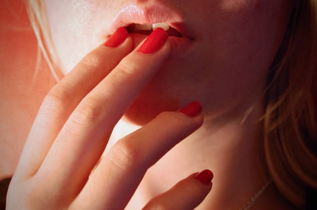photo of woman's fingers touching her lips