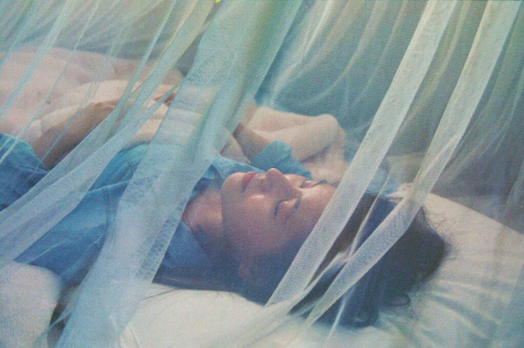 photo of woman sleeping under mosquito net