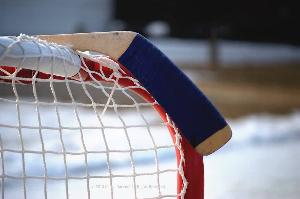photo of hockey goal with hockey stick resting on top