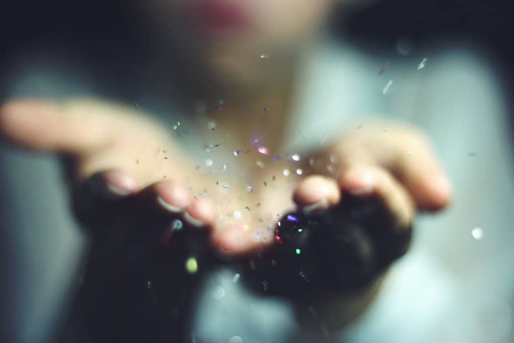 photo of person blowing glitter off of their hands
