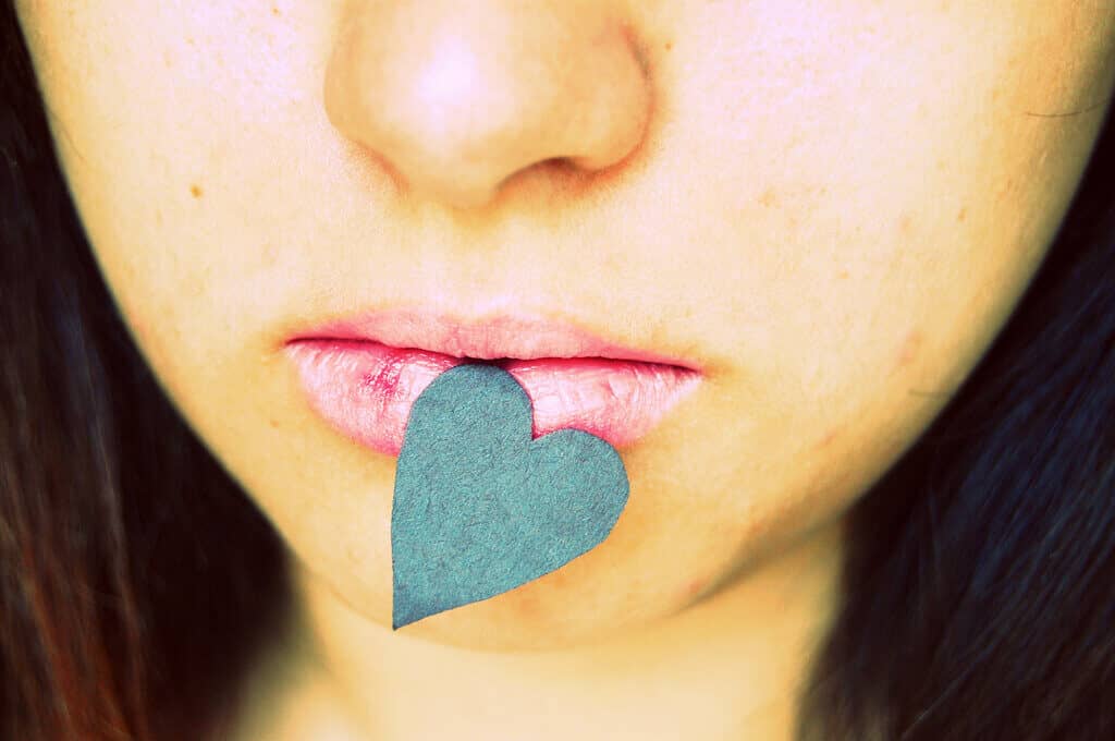 photo of woman with a paper heart attached to her lower lip