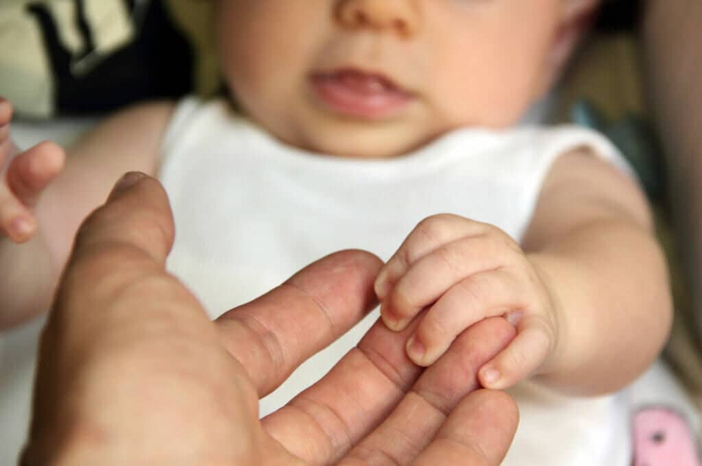photo of baby holding an adult's fingers