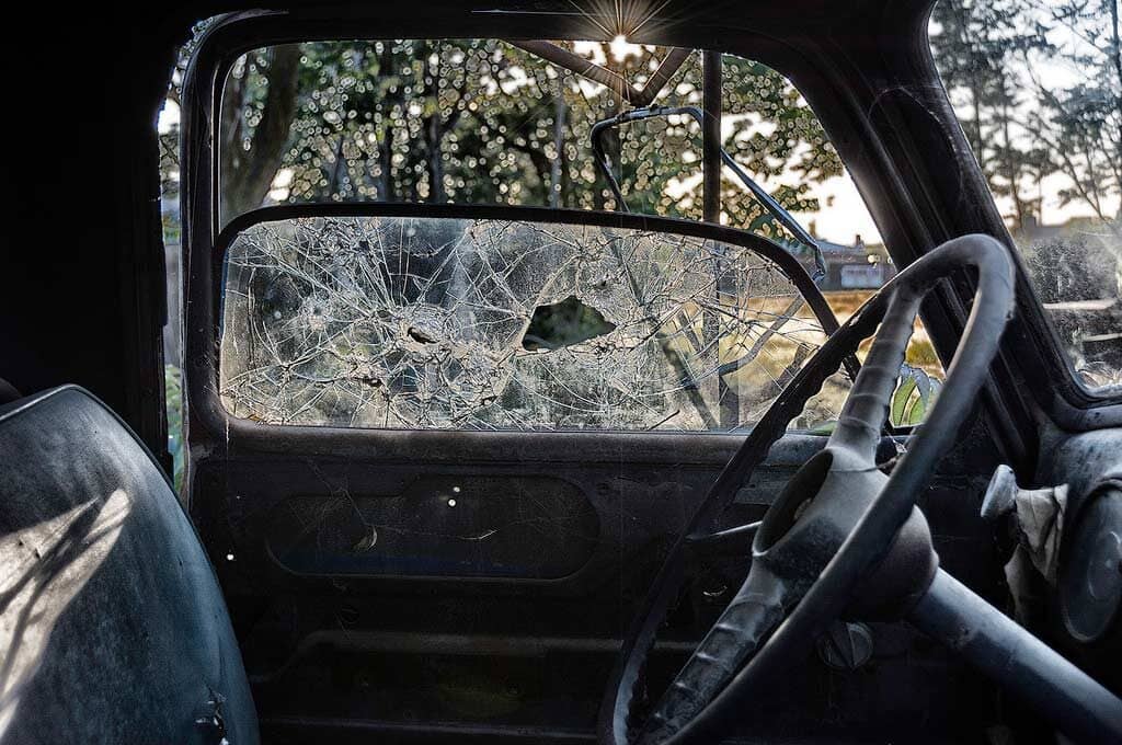 photo from inside of vehicle with a broken window next to steering wheel