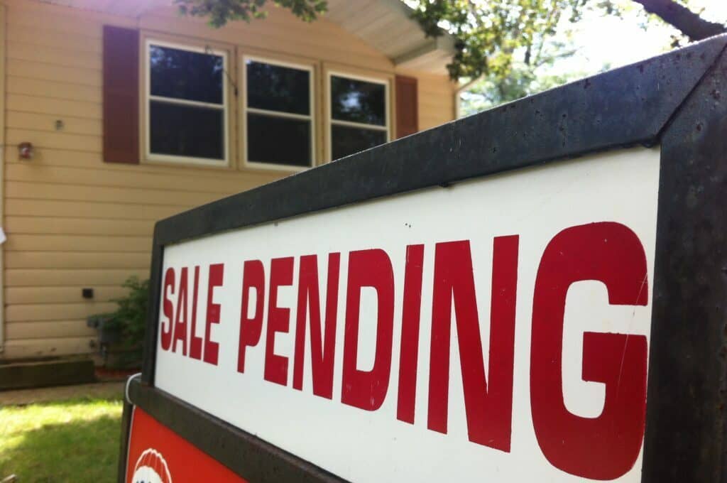 photo of house for sale with a "sale pending" sign on the front lawn