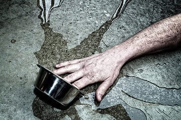 photo of hand tipping over silver bowl containing water