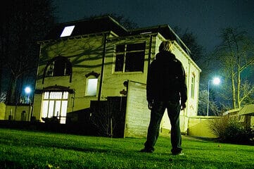 photo of man standing in front of a house at night