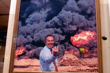 photo of a man taking a selfie in front of apocalyptic art piece on wall