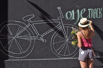 woman drawing a bicycle in chalk on a wall