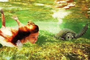 image of girl swimming underwater with a sea turtle