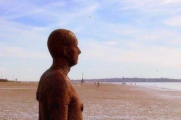 metal man statue on a beach