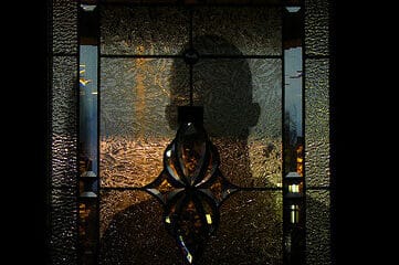 photo of a shadowy figure on the other side of a stained glass door