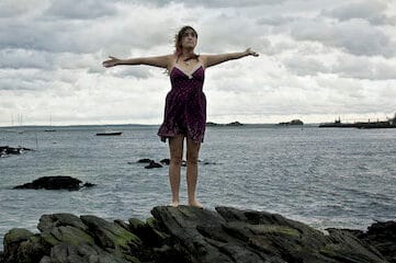 photo of a woman standing on a rocky beach